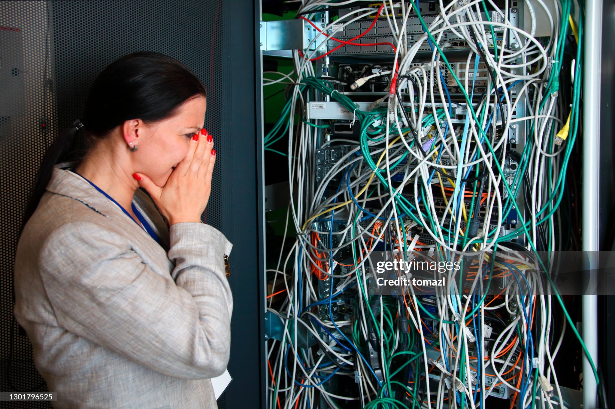 Computer rack in computer center full of wires. Big mess. Despair on a face of the woman.