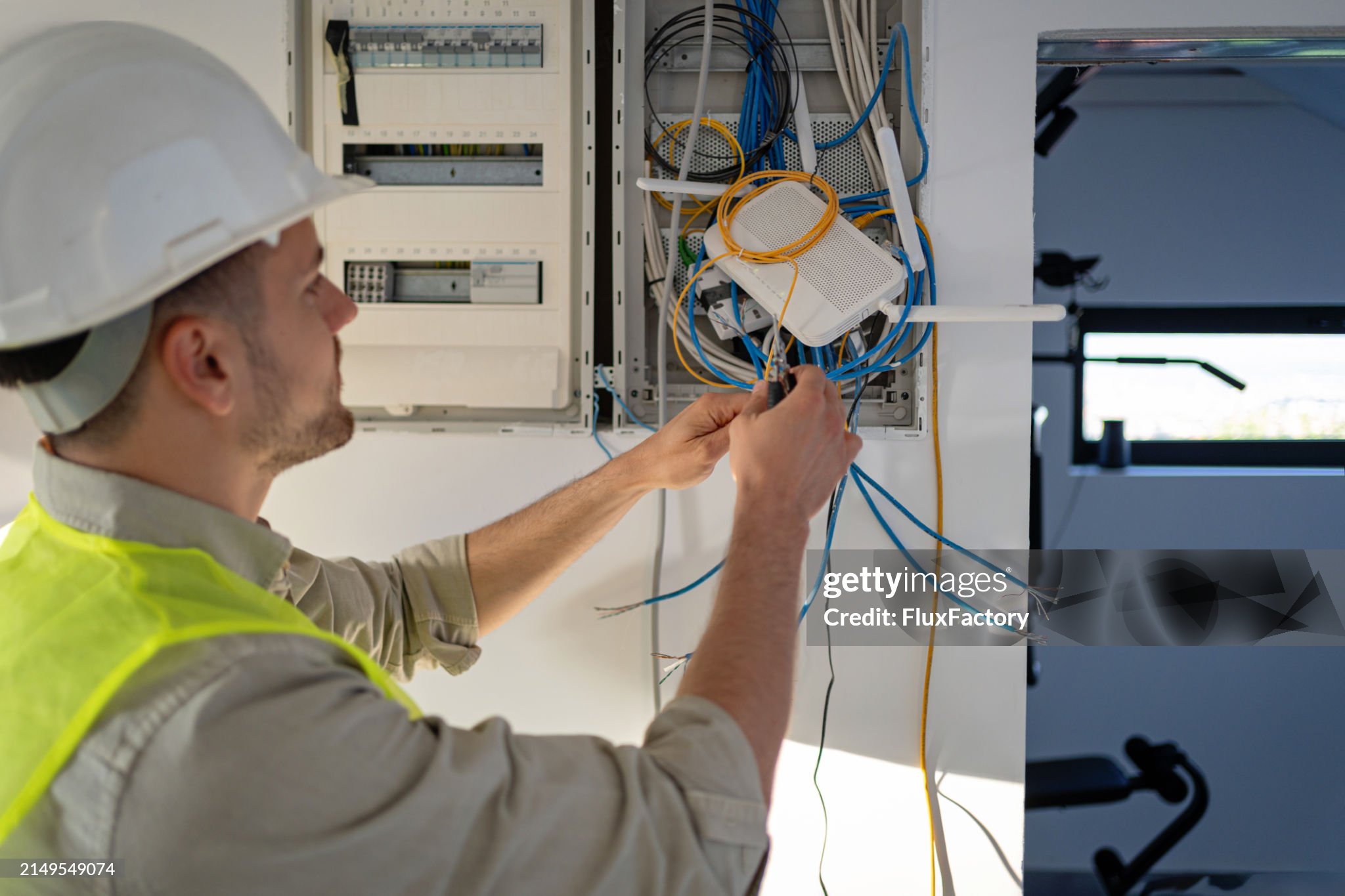 Young male Caucasian electrician working on the electrical installation of a new house, he is focused and dedicated to his work